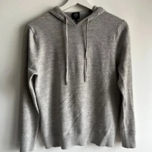 Merinoull hoodie - Merinoull hoodie i okej skick i grå färg, riktigt trendig just nu bra för dig som gillar grisch o laidback han på bilden är 174 passar S krympt L finns 2 mikro hål dm vid frågor 