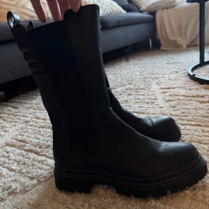 Svarta boots med dragkedja - Säljer ett par svarta boots i skinn med dragkedja på sidan. De har en robust sula och är perfekta för höst och vinter. Från Duffy, använda 1 gång.