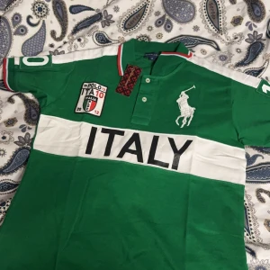 Chief keef polo  - Säljer en grön pikétröja från Polo med ett stort tryck av 'ITALY' på framsidan och nummer 10 på baksidan. Tröjan har vita och röda detaljer på kragen och ärmarna, samt en broderad logga på bröstet. 