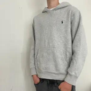 Säljer en snygg och bekväm grå hoodie från Ralph Lauren. Den har en klassisk design med en liten broderad logga på bröstet. Perfekt för både vardag och chill. Den passar perfekt för både höst och vinter. Supermjuk och skön att ha på sig