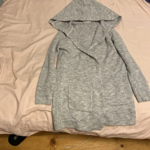  En grå lång kofta -  Säljer en lång grå kofta från Kappahl storlek 134 / 140.
