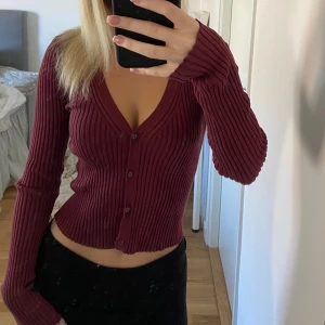 Kofta - Säljer denna fina mörkröda kofta från H&M. Den är lite åt det kortare hållet men inte för croppad. Storlek xs. Den är knappt använd  och därför i toppen skick. Köpt för 199kr.