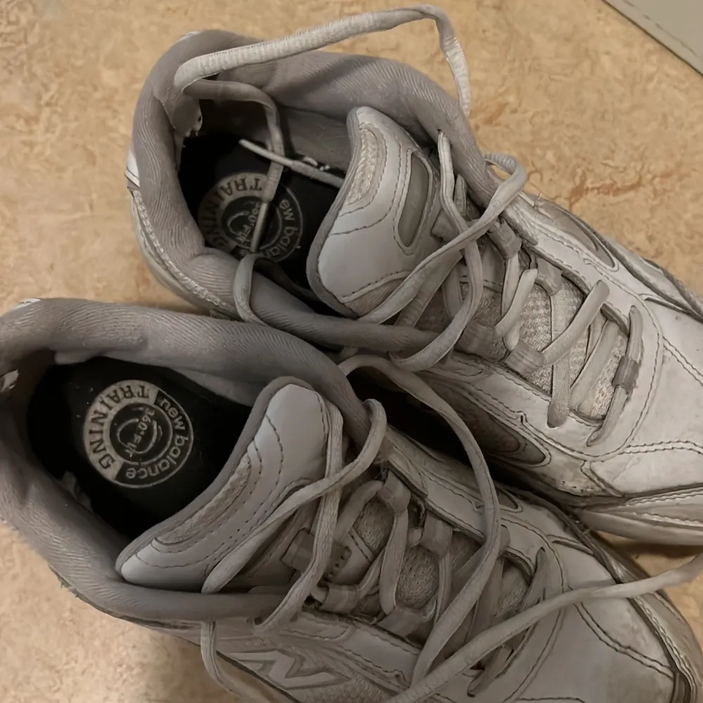 Säljer ett par vita sneakers från New Balance. De är välanvända men fortfarande bekväma och funktionella. Passar lika bra för träning som att använda till vardags!. Skor.