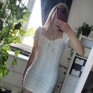 Klänning  - En vit klänning från H&M. Den har en roset och ett fint möster på tygget. Tygget är även rätt strechigt. Klänning är i bra skick 