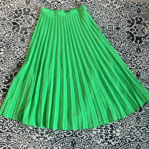 Grön plisserad kjol - Grön plisserad kjol från Stradivarius, inga tydligare tecken på använding. Strl M. På mig som är 178cm slutar den vid mitten av smalbenet.