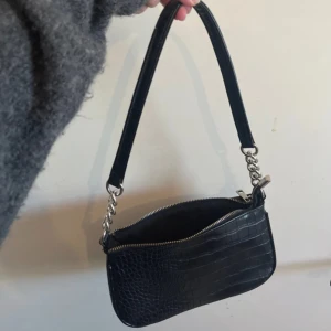 Axelremsväska svart med silver detaljer  - Svart axelremsväska med silver detaljer ifrån glitter. Bra skick. Rymmer ganska mycket. 