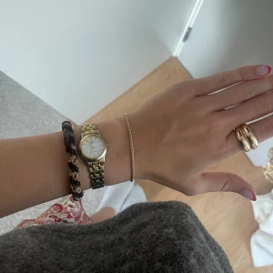 Guldfärgad klocka med vit urtavla - Snygg guldfärgad klocka , klassisk. Perfekt accessoar för både vardag och fest. Ganska använd men fortfarande i väldigt bra skick! Säljer då jag har en ny klocka och denna tyvärr inte kommer till användning längre