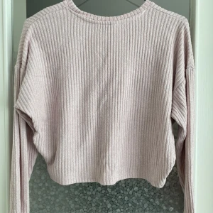 Ljusrosa ribbad croppad tröja - Säljer en superfin ljusrosa tröja som är ribbad och croppad. Den har långa ärmar och är perfekt för både höst och vår. Tröjan är i bra skick och väldigt bekväm att ha på sig. Passar perfekt till ett par höga jeans eller kjol!