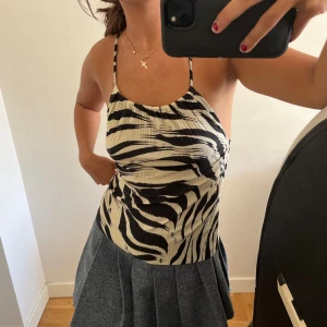 Zebramönstrad linne topp - Säljer en snygg zebramönstrad linne topp med smala axelband. Toppen är i svart och beige och har en tight passform. Perfekt för sommaren eller en festkväll! 🖤