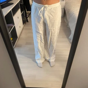 Vita linnebyxor från Sand - Säljer ett par superbekväma vita linnebyxor från Sand. De har en avslappnad passform med dragsko i midjan för extra komfort. Perfekta för en chill dag eller en somrig look. Byxorna är i ett lätt och luftigt material