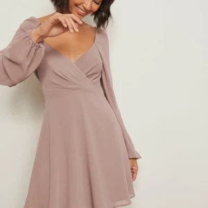 Beige omlottklänning med långa ärmar - Säljer en superfin rosa omlottklänning med långa ärmar. Den har en v-ringad design och är perfekt för sommar o fest! Klänningen har en lös passform och är gjord i ett mjukt material. Diskutera pris privat så kommer vi överens, (VILL FÅ SÅLD!)