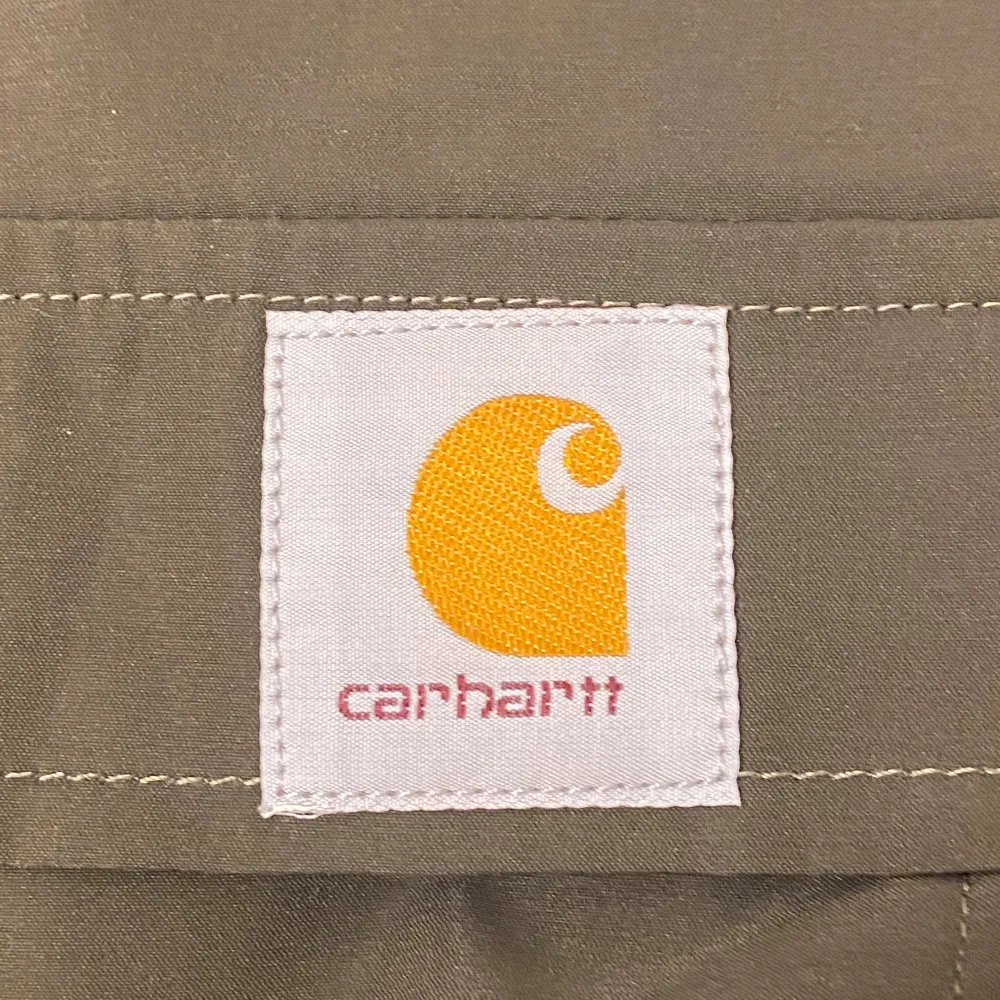 Säljer en grön vindjacka från Carhartt i storlek M. Jackan har en praktisk huva och en dragkedja framtill. Den är tillverkad i ett slitstarkt material och har ett meshfoder för extra komfort. Perfekt för vår och höst!. Jackor.