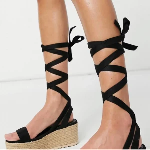 Svarta flatform sandaler - Svarta flatform- sandaler med knytning runt benet. Skorna är inköpta i mars 2021 från ASOS - Truffle Collection för 490kr. Skorna är helt oanvända! (Bild tagen från ASOS för att visa skorna bättre) 