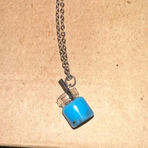 Halsband med blå flaska - Unikt halsband med en liten blå bobba dricka som hänge. Flaskan är gjord av plast och har en metallkedja. Perfekt för att ge en färgklick till din outfit!