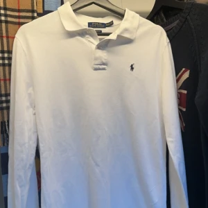 Vit Ralph Lauren Piké - Säljer denna vita långärmade Ralph Lauren pikén. Väldigt fint skick och inga tecken på användning.Storlek XL (18-20). Bara att skriva vid funderingar! 