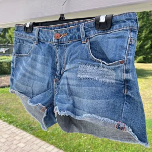 Blå jeansshorts - Ett par blå jeansshorts från H&M 💙 Shortsen är i storlek 40 och har en slitning på vänster ben. Fransiga kanter. Sanna i storleken!  Midja: 86 cm