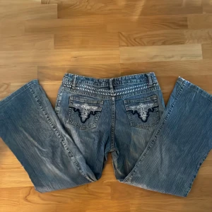 Ljusblå bootcut jeans - Bootcut midrise jeans med broderade fickor. Cirka W29-30 i midja. Lite kortare modell i benen