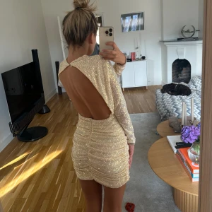 Glitter klänning -  Paljett/glitter klänning i benvit färg. Innertyg vilket gör att den ej är genomskinlig (bara på armarna) och kliar inte på kroppen. dragkedja bak i rumpan och sen 3 knappar i nacken. Öppen rygg. Jag är 1.68 cm.