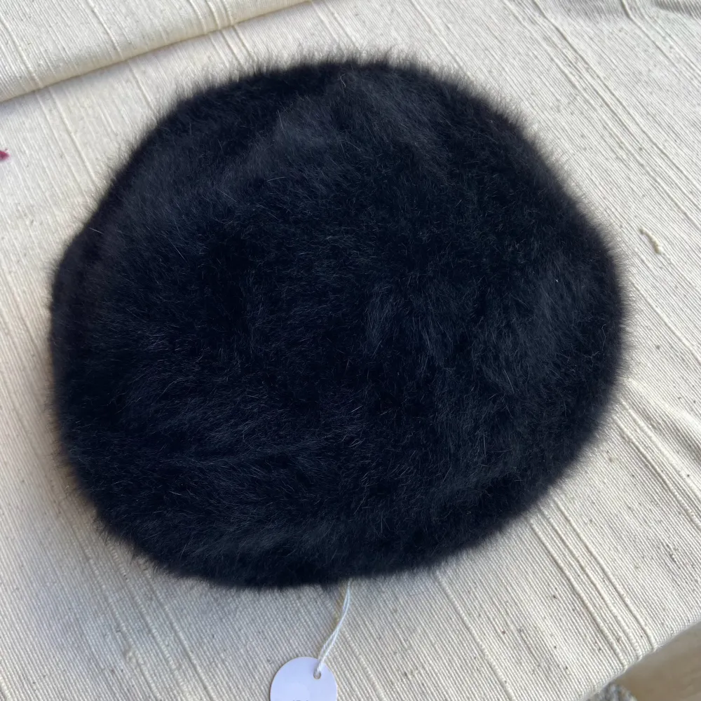 Svart fluffig mössa/basker från Kangol. Står ingen storlek, mätte omkretsen till 52 cm men jag har 58 cm huvud och kan ha den, så passar nog någon där emellan dock inte större. Jättefint skick! Dessa går ofta för runt tusenlappen!!. Övrigt.