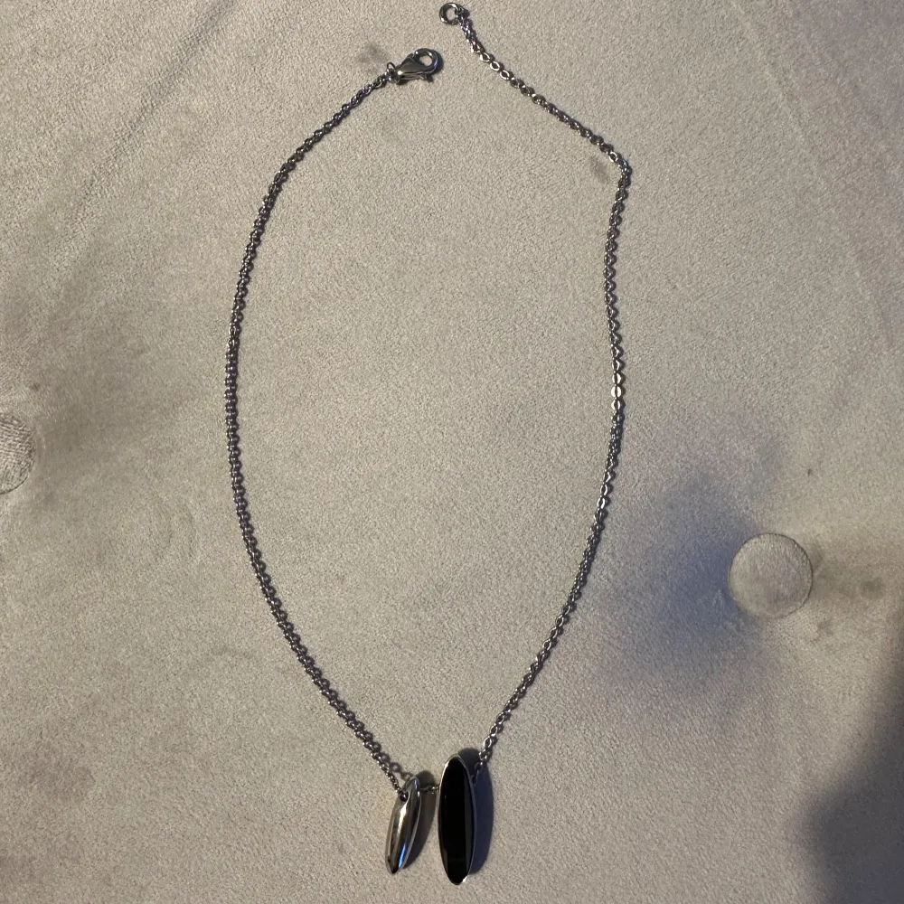 Märket är Calvin Klein. Säljer ett stilrent silverfärgat halsband med två ovala hängen. Kedjan är tunn och har en enkel karbinhake som lås. Hänget har en modern och minimalistisk design, perfekt för både vardag och fest. Halsbandet är i nyskick och redo att bäras med stil! Nypris är 950kr. Accessoarer.