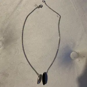 Märket är Calvin Klein. Säljer ett stilrent silverfärgat halsband med två ovala hängen. Kedjan är tunn och har en enkel karbinhake som lås. Hänget har en modern och minimalistisk design, perfekt för både vardag och fest. Halsbandet är i nyskick och redo att bäras med stil! Nypris är 950kr