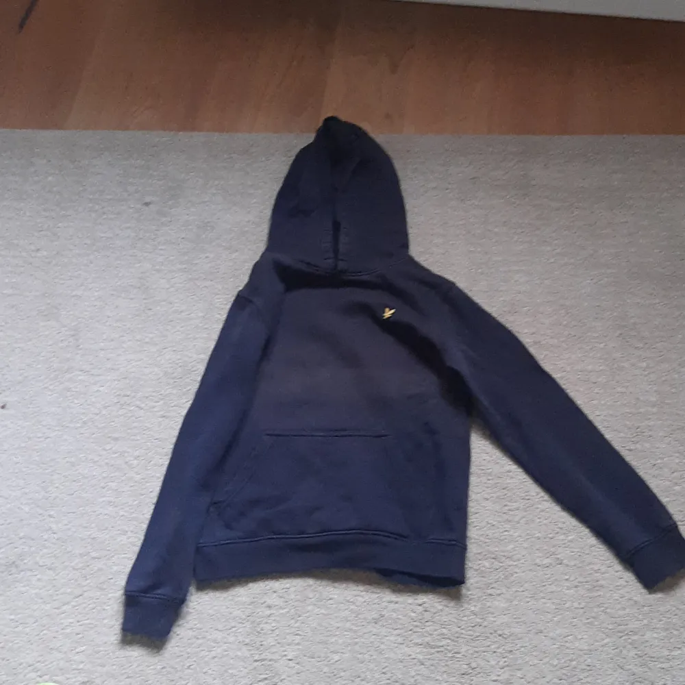 Säljer en snygg mörkblå hoodie från Lyle & Scott Junior. Den har en klassisk design med en liten gul logga på bröstet och en praktisk magficka. Perfekt för höst och vinter, och passar både till skolan och fritiden. Superbekväm och stilren!. Tröjor & Koftor.