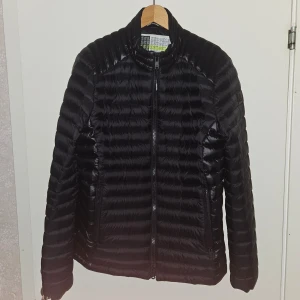 Moose Knuckles jacka - Stilren och lätt biker dunjacka i svart, i nyskick! Perfekt för höst och vår, håller dig varm utan att kompromissa med rörelsefrihet. Smidig dragkedja och diskreta fickor gör den både praktisk och snygg. Använd endast ett fåtal gånger.
