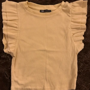 Ljusgul topp med volanger - Säljer denna ljusgula toppen med volanger från zara. Den är i fint skick och i storlek S men skulle även funka på någon som har XS i storlek. 