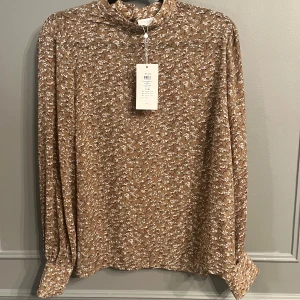 Vila Blus Ny med prislapp - Ny blus från Vila, prislapp kvar. Strl 44. Färg Tigers Eye.