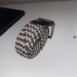 Flätat bälte - Tvär snyggt flätat bälte i färgerna vit, mörkblå och beige. Passar nästan alla jeans och är jätte skön att ha på då den är mjuk och elastisk. Man kan göra hål överallt eftersom att det är flätat. Skriv gärna vid fler bilder eller frågor 
