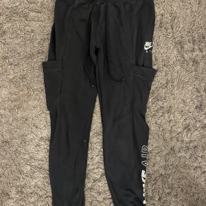 Svarta mjukisbyxor från Nike - Snygga svarta mjukisbyxor från Nike med 'Nike Air' tryck på benet. Byxorna har en bekväm passform med dragsko i midjan och praktiska sidofickor. 