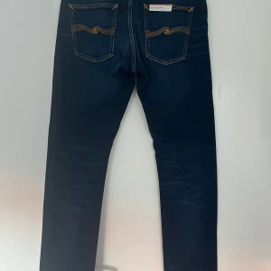 Mörkblå jeans från Nudie Jeans - Snygga mörkblå jeans från Nudie Jeans i modellen Lean Dean. Helt nya ek kommit till användning! Tillverkade av ekologisk bomull med en klassisk femficksdesign och orange sömmar. Perfekta för en stilren look.  Nypris 1500. Säljes  för 750 kr! 