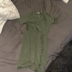 Grön omlottklänning från Hailys - Snygg grön omlottklänning från Hailys med korta ärmar och volangdetaljer. Perfekt för en avslappnad stil med en touch av elegans. Klänningen har en mjuk och bekväm passform.