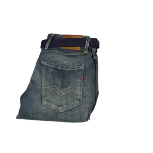 Blå jeans med bälte - Snygga blå jeans med ett mörkt bälte. Byxorna har en klassisk femficksdesign och en broderad detalj på bakfickan. Perfekta för en avslappnad stil.