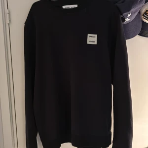 Svart tröja från Samsøe Samsøe - Snygg svart tröja från Samsøe Samsøe med rund hals och långärmad design. Perfekt för en stilren och enkel look. Tröjan har en diskret logga på bröstet.