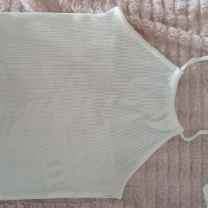 Vit ribbad linnetopp från Bik Bok - Säljer en stilren vit ribbad linnetopp från Bik Bok. Halter neck design med snörning bakom nacken. 