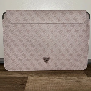 Beige/rosa laptopfodral från Guess - Jättefint beige/rosa laptopfodral från Guess med mönster och en triangel-logga på framsidan. Passar laptops som är 15,6 tum. Använd någon enstaka gång och är i mycket bra skick. Köptes för 800 kr. 