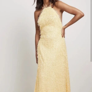 Gul långklänning med fransar - Säljer en fantastisk gul långklänning med fransar som ger en unik och festlig look. Klänningen är ärmlös och har en elegant halterneck-design. Perfekt för speciella tillfällen som bal!!! Ny med prislapp kvar