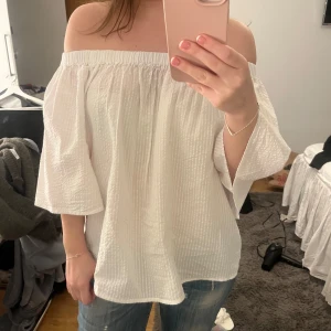 Vit offshoulder blus - Säljer en luftig vit offshoulder blus med trekvartsärmar. Perfekt för varma dagar och ger en avslappnad men stilren look. Passar bra till jeans eller kjol. Aldrig använd 