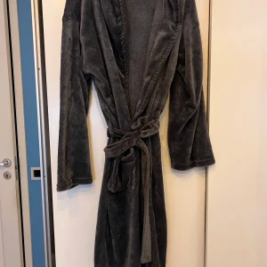 Mjuk grön morgonrock - Säljer en supermjuk och bekväm grön morgonrock med knytband i midjan från Rusta. Perfekt för att mysa runt hemma. Den har långa ärmar och har dtt fluffigt material. Storlek M