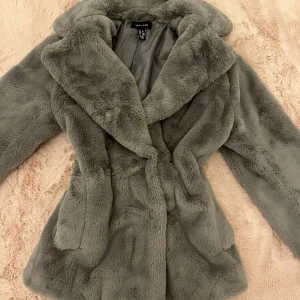 Grå pälsjacka - Snygg grå pälsjacka, med knappar, jättebra skick strl XS. Längd: 65cm