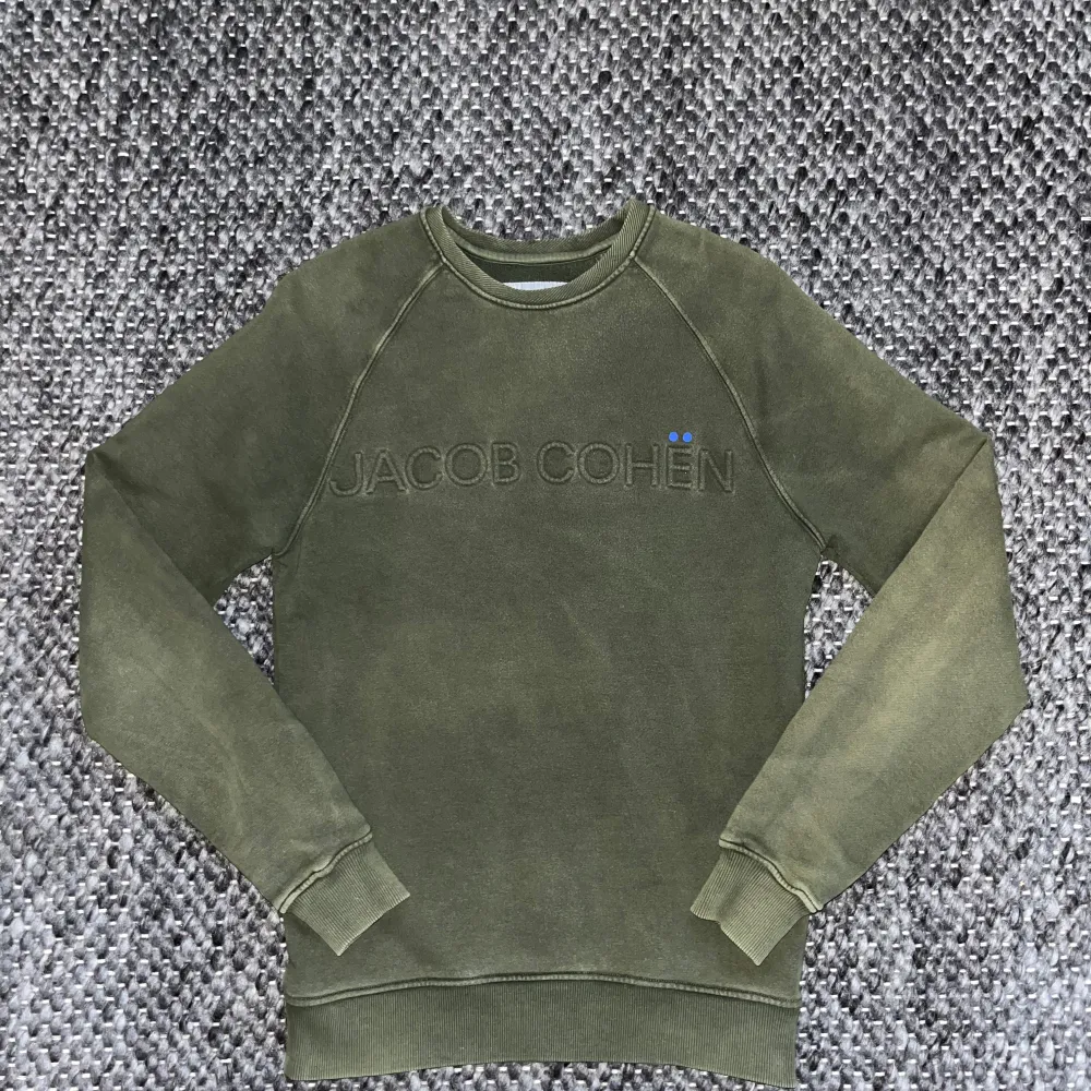 Säljer en stilren olivgrön sweatshirt från Jacob Cohën med broderad logotyp på bröstet. Tröjan har en lite tvättad look perfekt till en avslappnad stil! Storlek S, pris kan diskuteras, skriv pm vid fler frågor😁. Neuletakit & Villapaidat.