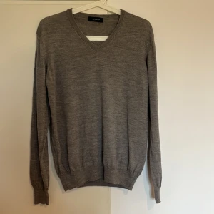 Grå v-ringad tröja från Sand - Snygg och stilren grå tröja från Sand med v-ringning. Perfekt för en klassisk look. Tröjan har långa ärmar och är tillverkad i ett mjukt material som ger en bekväm passform.