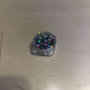 Glitter - En liten burk med flerfärgad glitter Perfekt för att lägga till en glittrig touch till din sminkning men även perfekt för nagel dekorationer. Kommer i en praktisk genomskinlig behållare.