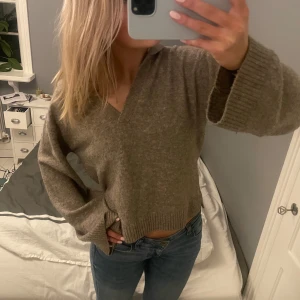 Brun stickad tröja med v-ringning - Säljer en mysig brun stickad tröja med v-ringning. Tröjan har långa ärmar och ribbade muddar vid ärmslut och nederkant. Perfekt för kyligare dagar.