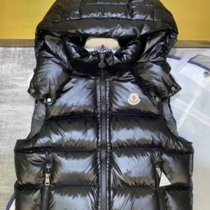 Svart dunväst från Moncler - Snygg svart dunväst från Moncler med glansig yta och dragkedja framtill. Västen har en hög krage och två praktiska fickor med dragkedja. Perfekt för kyligare dagar när du vill hålla stilen.