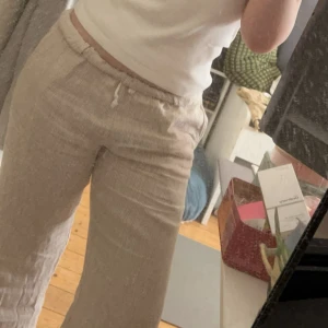 Randiga linnebyxor från Brandy Melville - Säljer ett par bekväma och stilrena randiga byxor från Brandy Melville. Byxorna är beige med vita ränder och har en avslappnad passform med dragsko i midjan för justerbarhet. Perfekta för en avslappnad look.