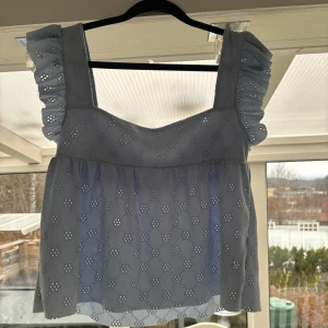 Ljusblå topp med volangärmar från Nelly - Söt ljusblå topp från Nelly med volangärmar och broderade detaljer. Toppen har en fyrkantig urringning och är perfekt för vår och sommar. Den är tillverkad i ett lätt och luftigt material.