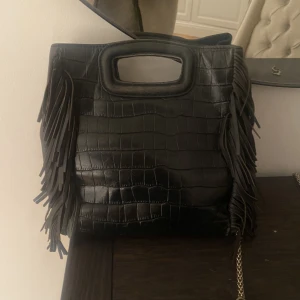 Maje väska  - Så fin svart Maje väska i den större modellen❤️så användbar och den rymmer mycket!!  De enda teckna på användning är på handtaget vilket man inte ser när man väl bär väskan🥰 dustbag tillkommer också men inte bandet då jag råkat tappa bort det