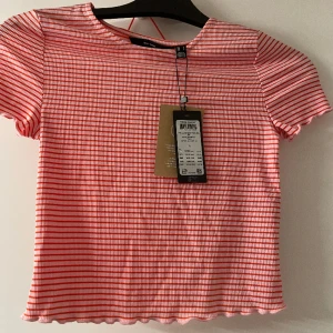 Randig tröja  - En röd/rosa randig croppad T-shirt. Aldrig andvänd prislapp kvar. En färgglad och fina tröja. 